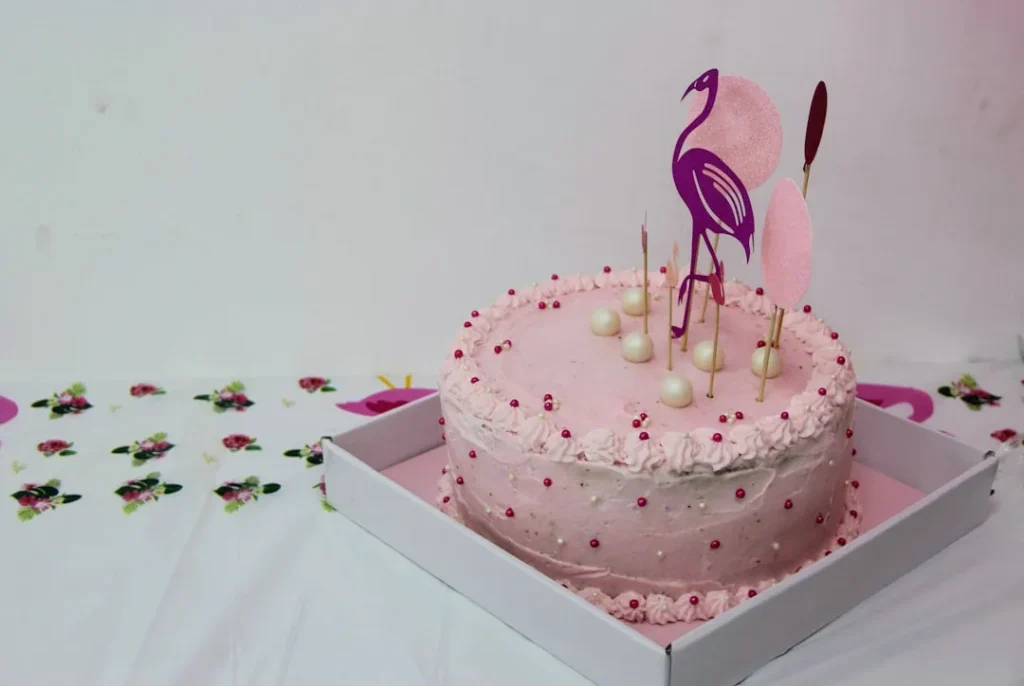 A pink cake with a flamingo on top of it