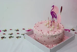 A pink cake with a flamingo on top of it
