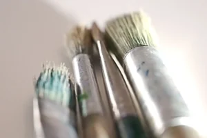 Close-up of several paint brushes on a white surface.
